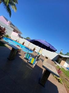 a bench with an umbrella next to a swimming pool at Pousada São Gabriel in Ametista do Sul