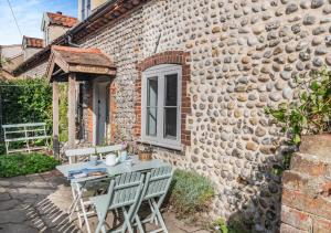 a table and chairs outside of a stone house at 1 Cutty Sark Cottages in West Runton