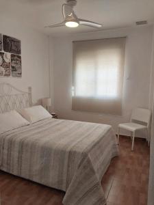 Un dormitorio con una cama y un ventilador de techo. en Apartamento Urb La Tortuga I, en Tarifa