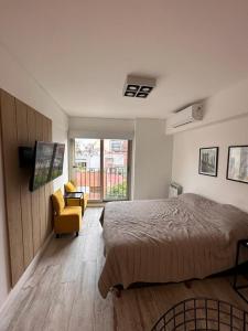 a bedroom with a large bed and a yellow chair at STUDIO BARRACAS in Buenos Aires