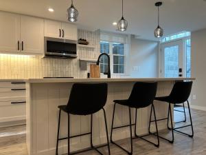 a kitchen with four black chairs at a counter at The Croft House - 2 Bedroom 1 Bathroom Suite in Burlington