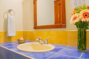 baño con lavabo y jarrón de flores en Hacienda Grande Hotel, en Quetzaltenango