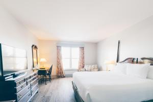 Un dormitorio con una cama, un escritorio y un televisor. en The Loyalist Country Inn & Conference Centre, en Summerside