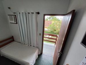 a room with a bed and a door with a window at Pousada da Jaqueira - EPP in Rio das Ostras