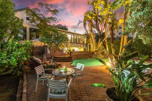 un patio trasero con mesa, sillas y piscina en Mediterranean Villa Guesthouse en Ciudad del Cabo