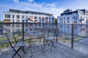 een balkon met 2 stoelen en een tafel en 2 gebouwen bij Nowe Ptasie, Osiedle Ptasie, apartment 29, NEW - LUX - PARKING in Katowice