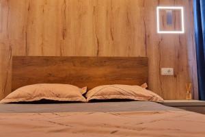 a bed with a wooden headboard and two pillows at Urban Retreat Barlad in Bîrlad +2 photos