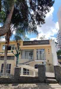 uma árvore em frente a um edifício com uma cerca em Joshua Tree Hostel - Curitiba em Curitiba