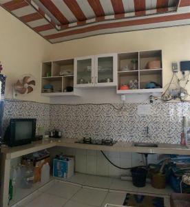 a kitchen with white cabinets and a tv on a wall at Butterfly Kost Tulungagung in Ngantru