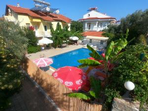 a swimming pool with two umbrellas next to a house at Sarıhan Apart Otel in Oludeniz