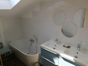 La salle de bains est pourvue d'une baignoire, d'un lavabo et d'un miroir. dans l'établissement Charmante maison dans joli village, à Vouhé
