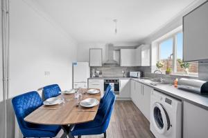 a kitchen with a wooden table and blue chairs at 3 bedrooms with parking ideal for long stays in Peterborough