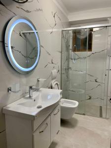 uma casa de banho com um lavatório, um chuveiro e um espelho. em Relaxing Getaway em Gjirokastër