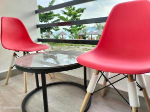 two red chairs and a glass table on a balcony at White Stone Beach Resort in Mbita