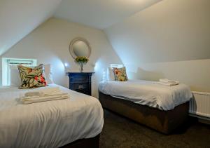 1 dormitorio con 2 camas y espejo en la pared en Gardeners Cottage - Nowton Park en Rushbrooke