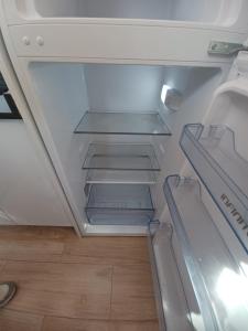an empty refrigerator with its door open on a wooden floor at Apartamento jardin del mar 7.5 in La Manga del Mar Menor
