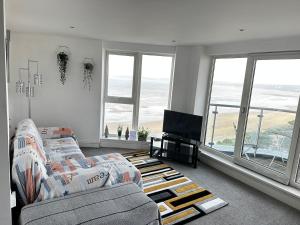 sala de estar con sofá y TV de pantalla plana en Stunning Ocean & City View APT, en Swansea