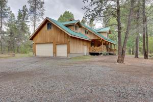 a large house with a garage in the woods at Pet-Friendly House with Deck Near Crater Lake! in Fort Klamath