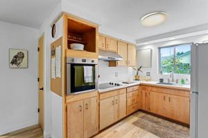 eine Küche mit Holzschränken, einer Spüle und einer Mikrowelle in der Unterkunft The Jasmine House in Eugene