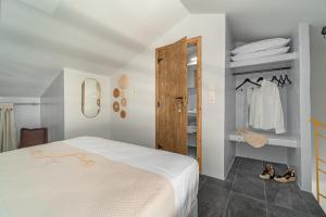 1 dormitorio con cama blanca y armario en La Perla Suites, en Agioi Apostoli