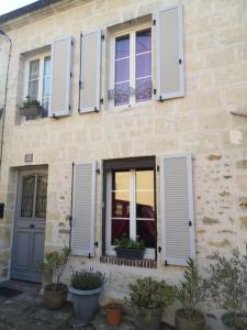 a building with white shuttered windows and potted plants at Au cœur de Mortagne, un balcon sur le Perche in Mortagne-au-Perche
