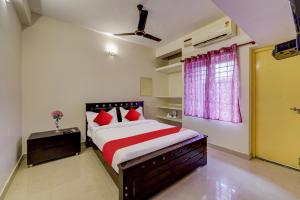 a bedroom with a bed with red pillows and a window at Senthamizh Residency in Chennai
