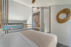 1 dormitorio con cama blanca y ventana en La Perla Suites, en Agioi Apostoli