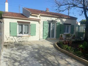 een wit huis met groene luiken en een patio bij Maisonnette in Corbeil-Essonnes