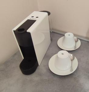 a white coffee maker and two cups on plates at Menrat in Novi Sad