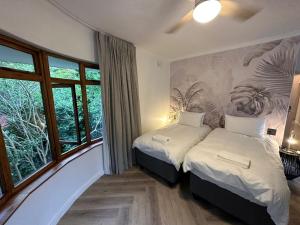 a bedroom with two beds and a mural of plants at WunderLux in Cape Town
