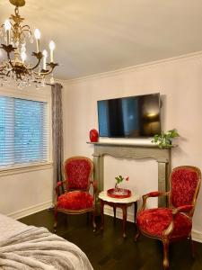 多倫多的住宿－市中心維多利亞式豪華療養旅館，一间卧室配有两把椅子、一张桌子和一台电视。
