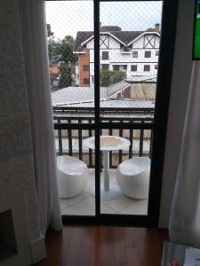 een kamer met uitzicht op een balkon met een tafel bij Apto Deslumbrante em Capivari proximo a BADEN BADEN in Campos do Jordão