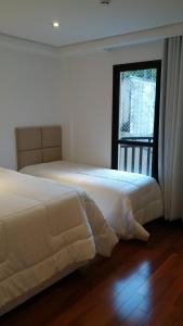 2 camas num quarto com uma janela em Apto Deslumbrante em Capivari proximo a BADEN BADEN em Campos de Jordão