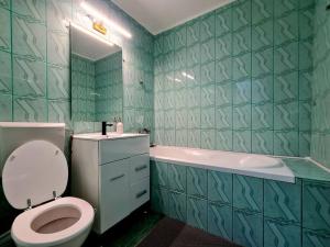 a green tiled bathroom with a toilet and a tub at Urban Nest Barlad in Bîrlad