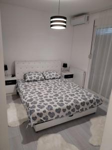a bedroom with a bed with a black and white comforter at Bella apartman in Mladenovac