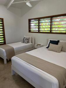 two beds in a room with two windows at Lope Lope Beach Bungalows in Luganville