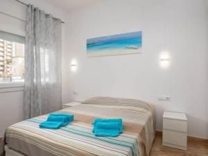 a bedroom with a bed with two blue pillows on it at Apartamento a 50m de la playa in Platja  d'Aro