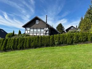 ein Haus mit einer Hecke vor einem Hof in der Unterkunft Holiday home with private garden in Winterberg