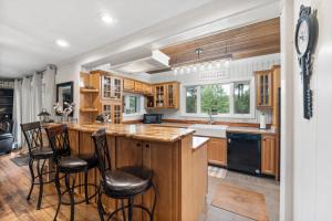 a kitchen with wooden cabinets and a island with bar stools at Refuge Ranch Retreat Log Cabin Lake 53+ Acres in Locust Grove