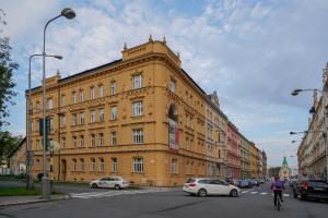 een groot geel gebouw in een stadsstraat met auto's bij Lucy's Apartments 2 in Olomouc