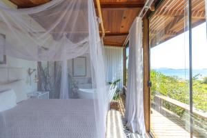 a bedroom with a bed and a tub and a window at Gringos Boutique Hotel in Búzios