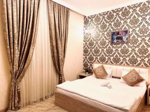 a bedroom with a bed and curtains in it at Sebail Inn Hotel in Baku