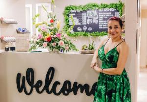 a woman in a green dress standing in front of a welcome sign at Caribbean Palm Village Resort in Palm-Eagle Beach