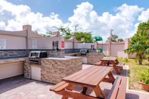 a patio with two picnic tables and a grill at Caribbean Palm Village Resort in Palm-Eagle Beach