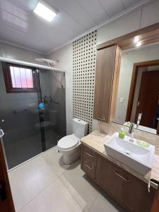 ein Bad mit einem WC, einem Waschbecken und einer Dusche in der Unterkunft Casa mais Central de Gramado in Gramado