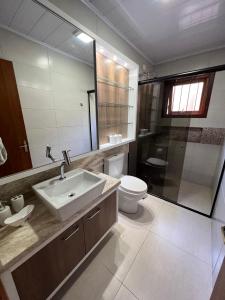 a bathroom with a sink and a toilet and a mirror at Casa mais Central de Gramado in Gramado +22 photos