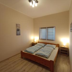 佐馬爾迪的住宿－Zafír Vendégház，一间卧室配有一张带两盏灯的床和一扇窗户。