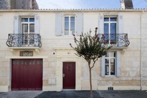 un bâtiment avec deux portes rouges et un arbre à l'avant dans l'établissement Appartement T2 de haut standing classé trois étoiles, hypercentre Rochefort, arrivée autonome, à Rochefort