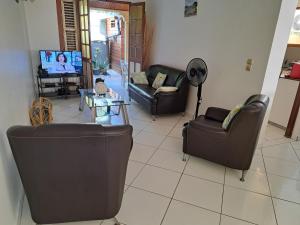 sala de estar con 3 sofás y TV en MAISON de VACANCES ANSES D'ARLET en Les Anses-dʼArlets