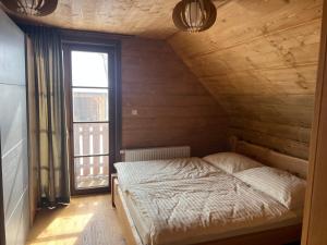 a bed in a room with a large window at Cabin House Čičmany- Relaxačné zariadenie s ubytovaním in Čičmany